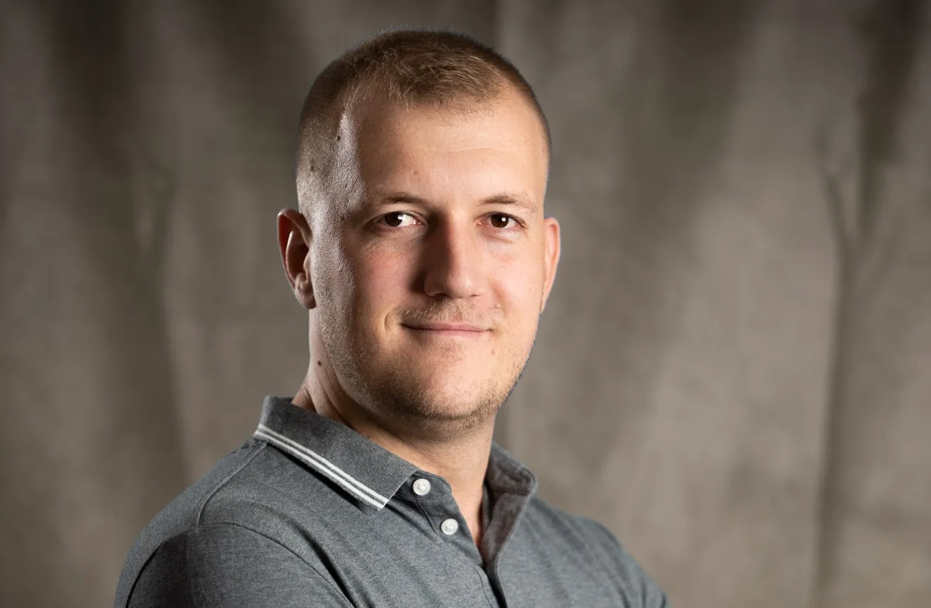 Business-Headshot eines jungen Mannes vor braunem Hintergrund